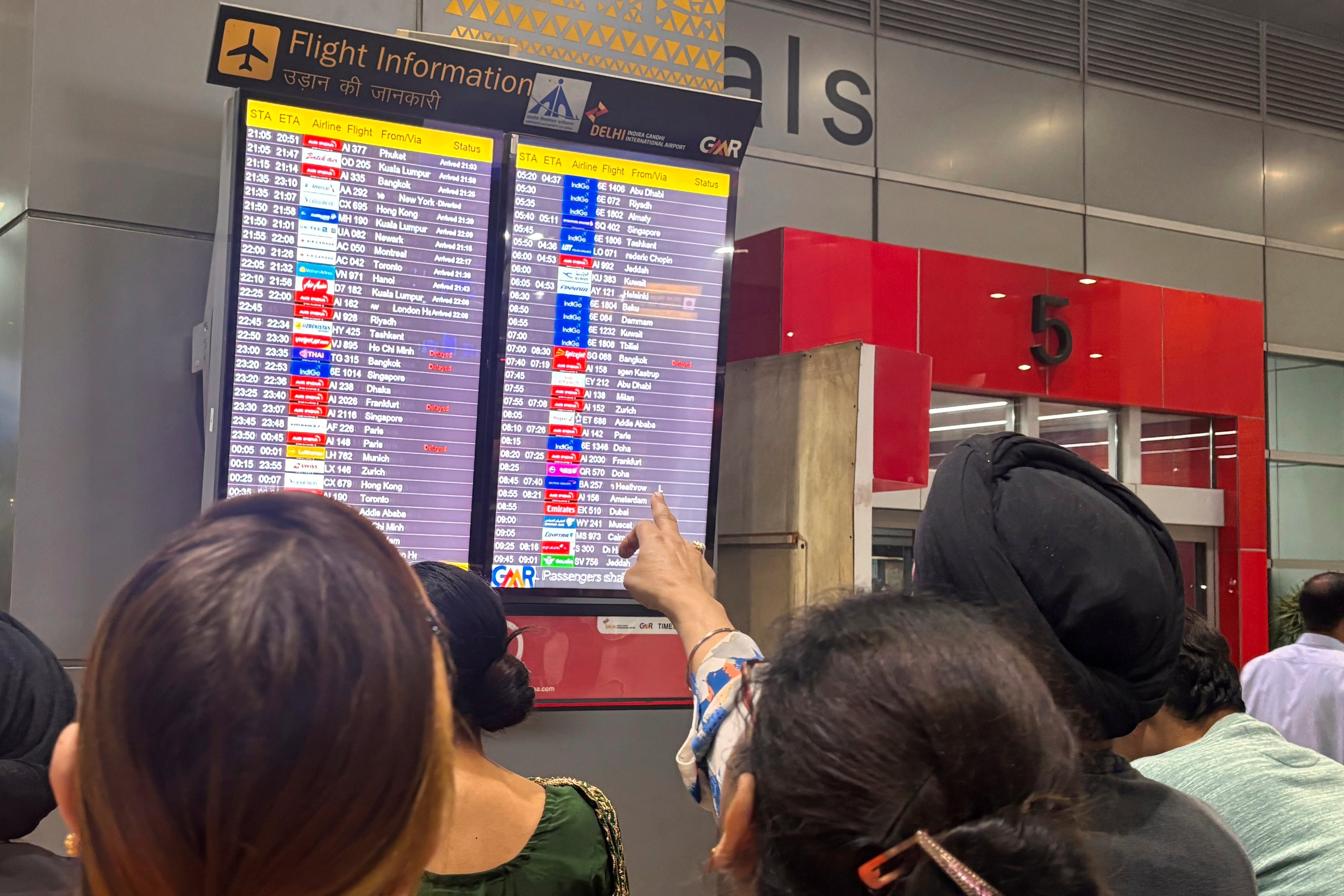 Personas observan una pantalla en el aeropuerto internacional de Nueva Delhi. (AP Foto/Manish Swarup)