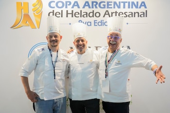 Tres chefs sonriendo, vistiendo uniformes blancos y gorros de chef, posan frente a un cartel con el logo y el texto "Copa Argentina del Helado Artesanal"