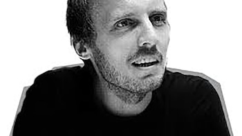 Primer plano en blanco y negro de Michal Hvorecký, un hombre con cabello corto y barba. Viste una camiseta oscura y mira ligeramente a la derecha con la boca entreabierta