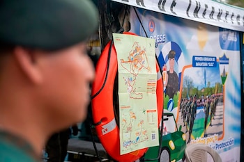 Persona con uniforme verde observa un salvavidas naranja con un mapa de Tikal y Biosfera Maya, frente a un cartel de CONRED y la Primera Brigada de Infantería