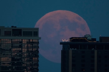 La luna llena sale tras los edificios de apartamentos del centro de Kansas City, Misuri, antes de un eclipse lunar el jueves 27 de agosto de 2026 (AP/Charlie Riedel)