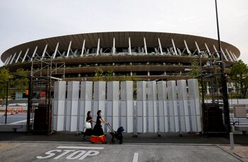 Peatones con máscaras protectoras caminan frente al Estadio Nacional, el estadio principal de los Juegos Olímpicos y Paralímpicos de Tokio 2020 en Tokio, Japón, el 7 de julio de 2021. REUTERS / Kim Kyung-Hoon