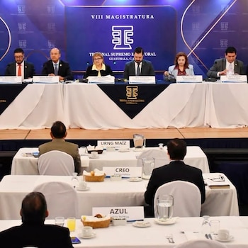 Seis autoridades en una mesa del Tribunal Supremo Electoral frente a asistentes sentados en mesas con rótulos de organizaciones políticas