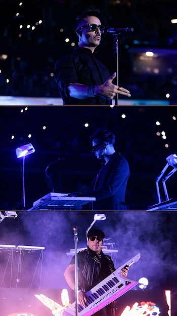 Tres músicos en el escenario, iluminados por luces de concierto. Uno canta al micrófono, otro toca un teclado y el tercero una keytar