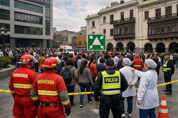 Multitud de personas evacúa en plaza, bomberos, policías, personal de salud, edificio moderno, edificios coloniales, ambulancia, señal de evacuación, cinta amarilla.