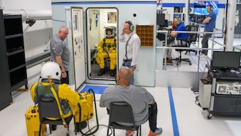 Personal técnico supervisa pruebas con trajes de presión en una instalación de simulación