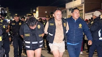 Agentes policiales con chalecos del Grupo Terna escoltan a dos hombres intervenidos por una calle durante la noche