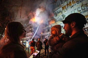 Victoria Deineko, su esposo, Ievhen Deineko y su hija, Mia, se ven junto a un edificio residencial de varias plantas dañado en Kiev, Ucrania, el martes 13 de octubre de 2026 (AP/Evgeniy Maloletka)