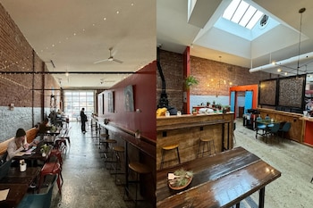 Interior amplio de Café Corazón con paredes de ladrillo visto y rojo, mesas con clientes, una barra de madera, obras de arte, puertas azules y una claraboya