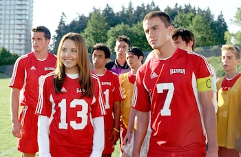 Amanda Bynes y Channing Tatum visten camisetas rojas de fútbol con los números 13 y 7 junto a otros integrantes del equipo en un campo
