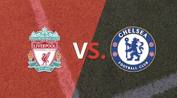 Escudos de Liverpool Football Club y Chelsea Football Club separados por el texto VS sobre un fondo de césped dividido en rojo y negro.
