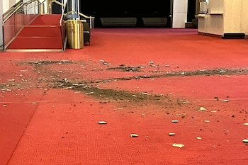 Escombros y fragmentos de techo caídos sobre una alfombra roja en el interior de un edificio junto a unas escaleras