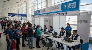 Personas en fila en un aeropuerto de Guatemala se acercan a mesas donde personal del Tribunal Supremo Electoral las empadrona.