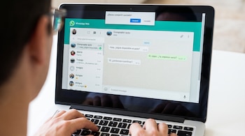 Manos de una persona sobre una computadora portátil que muestra WhatsApp Web y una ventana emergente para compartir pantalla.