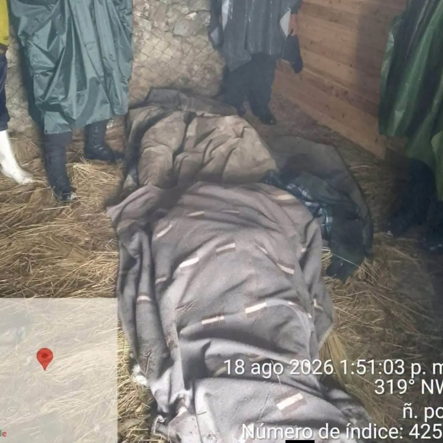 Un porteador fallecido se encuentra cubierto en el suelo de paja en Cusco, rodeado por personas que visten ropa de lluvia. (PNP)