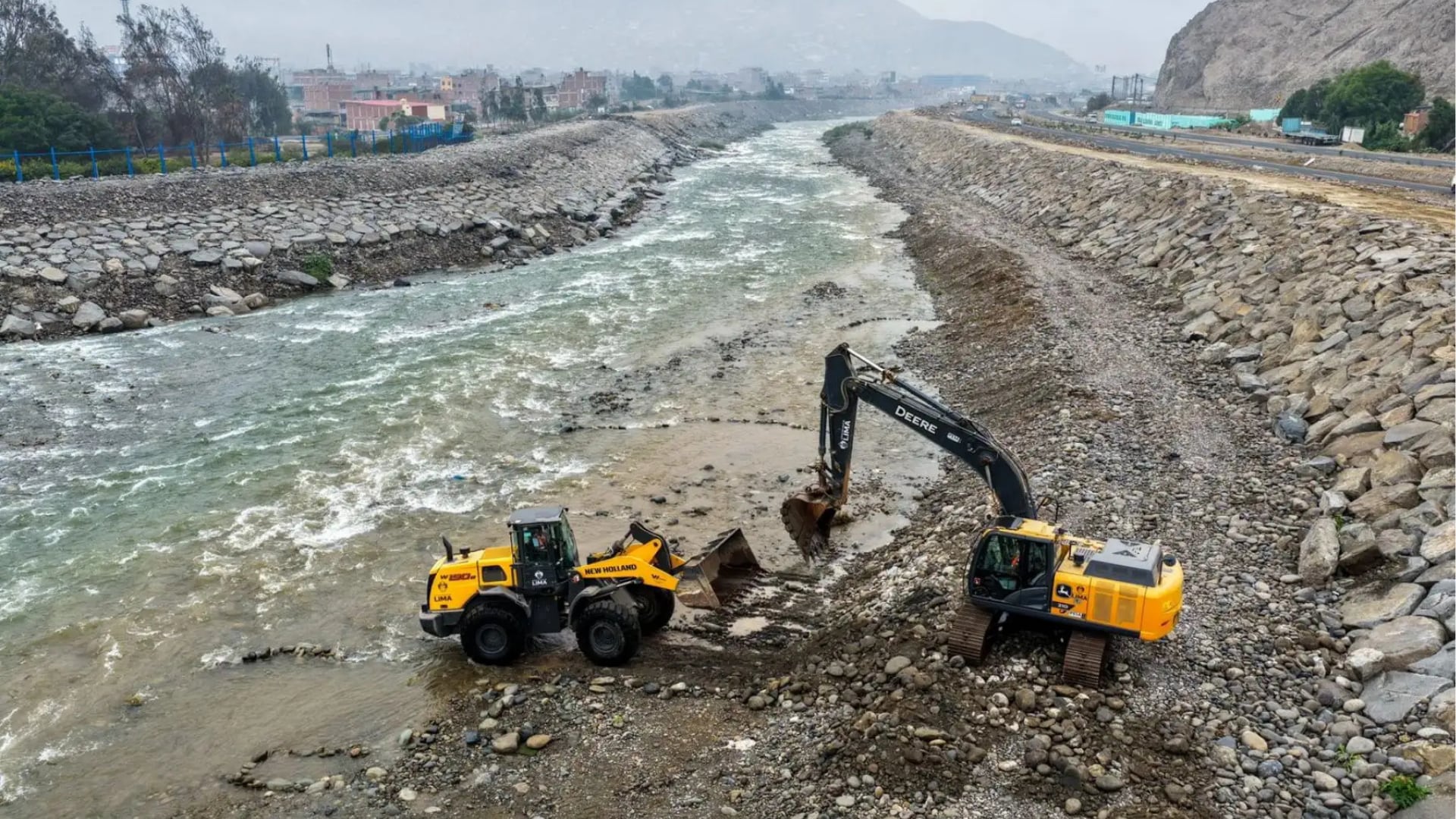 Maquinaria pesada efectúa trabajos de descolmatación en el cauce de un río reforzado con piedras, como parte de la estrategia del gobierno peruano frente al Fenómeno El Niño. (Agencia Andina)