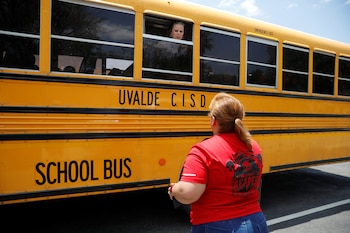 Un empleado de la escuela habla a través de la ventana de un autobús escolar con uno de los padres cerca de la escena de un presunto tiroteo (REUTERS/Marco Bello)