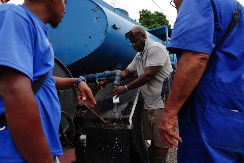 Conductores se preparan para beber agua mientras esperan su turno para llenar camiones de agua en La Habana (REUTERS/Alexandre Meneghini/Archivo)