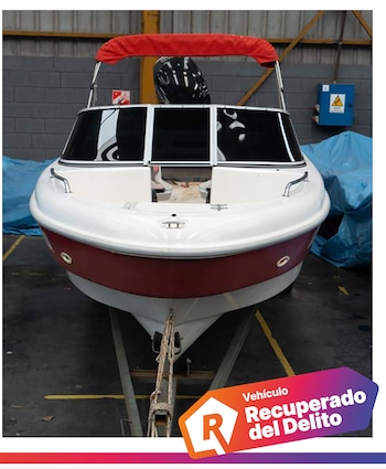 Lancha blanca y roja sobre un remolque en un almacén con un logotipo que dice vehículo recuperado del delito