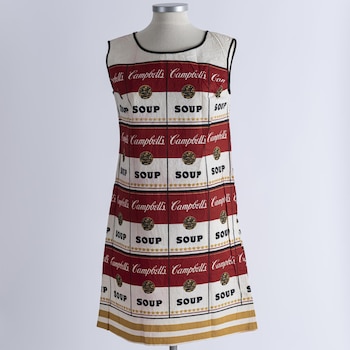 Un vestido sin mangas blanco con franjas rojas y el logotipo de sopa Campbell's repetido, exhibido en un maniquí gris