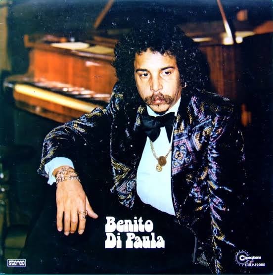 El cantautor Benito di Paula posa con ua saco estampado y corbata de lazo frente a un piano en la portada de su disco.