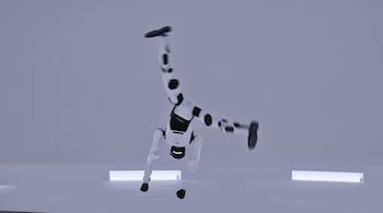 Un robot humanoide de color blanco y negro apoya las manos en el suelo durante un giro acrobático en un espacio iluminado