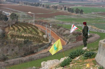 Un miembro de Hezbollah sostiene una bandera libanesa durante una ceremonia en la localidad libanesa del sur de Khiam, cerca de la frontera con Israel, el 3 de enero de 2021 (REUTERS/Aziz Taher)