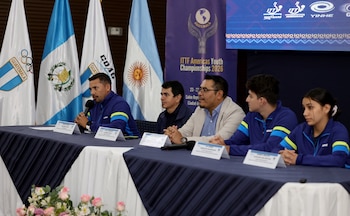 Cinco personas sentadas en una mesa con micrófonos. De fondo, banderas de Guatemala y Argentina, un cartel de evento y una pantalla con logos