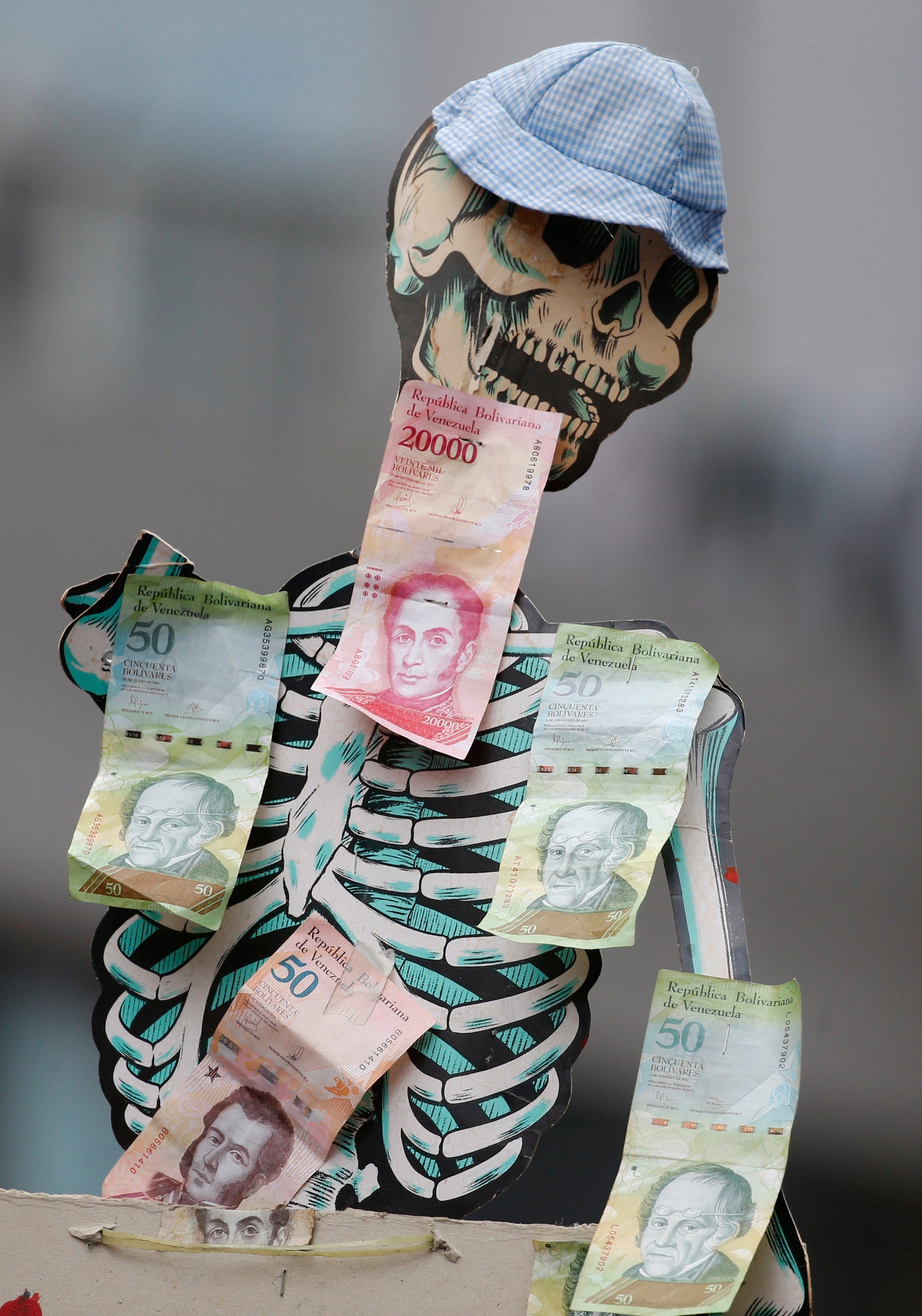 Un esqueleto adornado con billetes de bolívares para llamar la atención sobre la devaluación de la moneda y el hambre, en una marcha de oposición en Caracas. (AP Foto/Ariana Cubillos, Archivo)