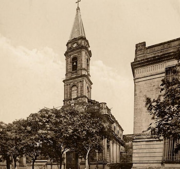 Fotografía antigua en tono sepia de la iglesia Spire, con campanario, aguja, reloj, campana, árboles y un edificio lateral