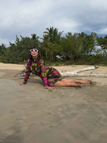 Recostada en la arena junto a un tronco de madera, Casán posó con el vestido floral transparente y lentes de sol blancos en una playa del Caribe