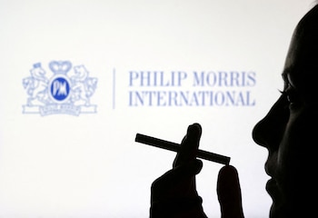FOTO DE ARCHIVO: Una mujer posa con un cigarrillo frente al logotipo de Philip Morris International en esta ilustración. REUTERS/Dado Ruvic/Ilustración/Foto de archivo