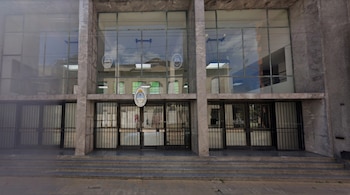 Edificio de mármol gris y grandes ventanales de vidrio, con escaleras, puertas enrejadas y la inscripción "Poder Judicial de la Nación".