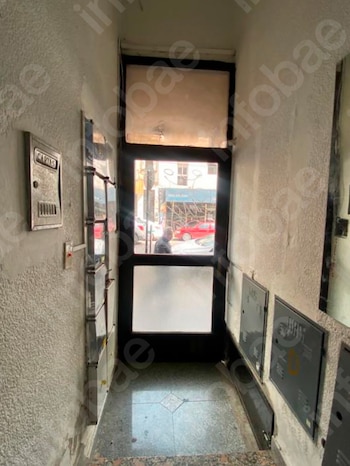 Un panel de vidrio fisurado y roto muestra grietas profundas y deja ver un automóvil gris estacionado frente a un edificio