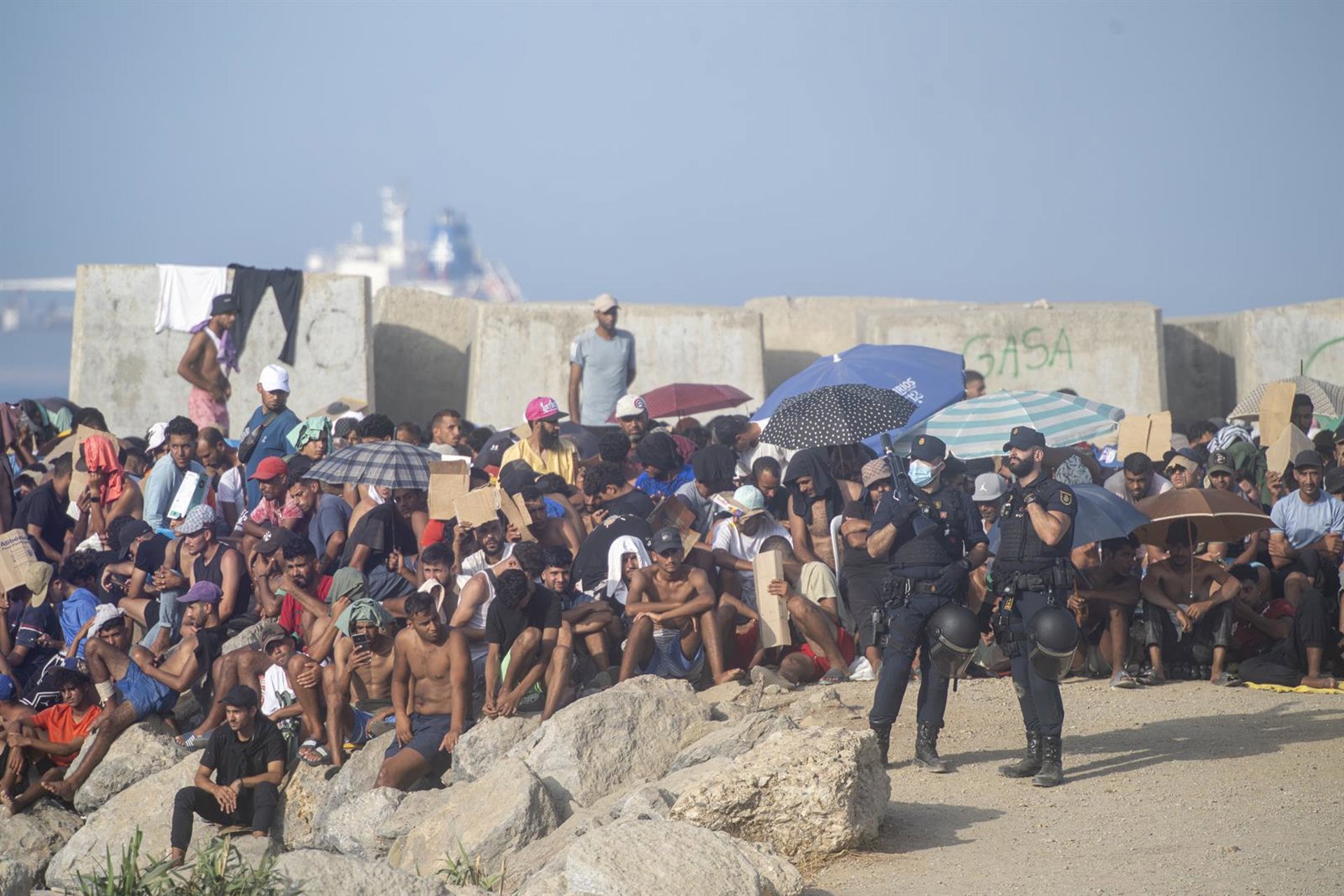 Decenas de migrantes vigilados por la Policía Nacional en las playas de Ceuta (Marcos Moreno - Europa Press)
