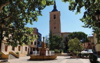 Una fuente con la iglesia de frente y el ayuntamiento a la izquierda.