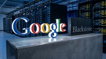 Logotipos de Google y Blackstone en primer plano sobre hormigón gris, con un centro de datos lleno de servidores, luces y cables visible al fondo.