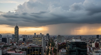Vista aérea de la Ciudad de México con la Torre Latinoamericana y otros rascacielos. Grandes nubes de lluvia oscuras cubren el cielo del atardecer.