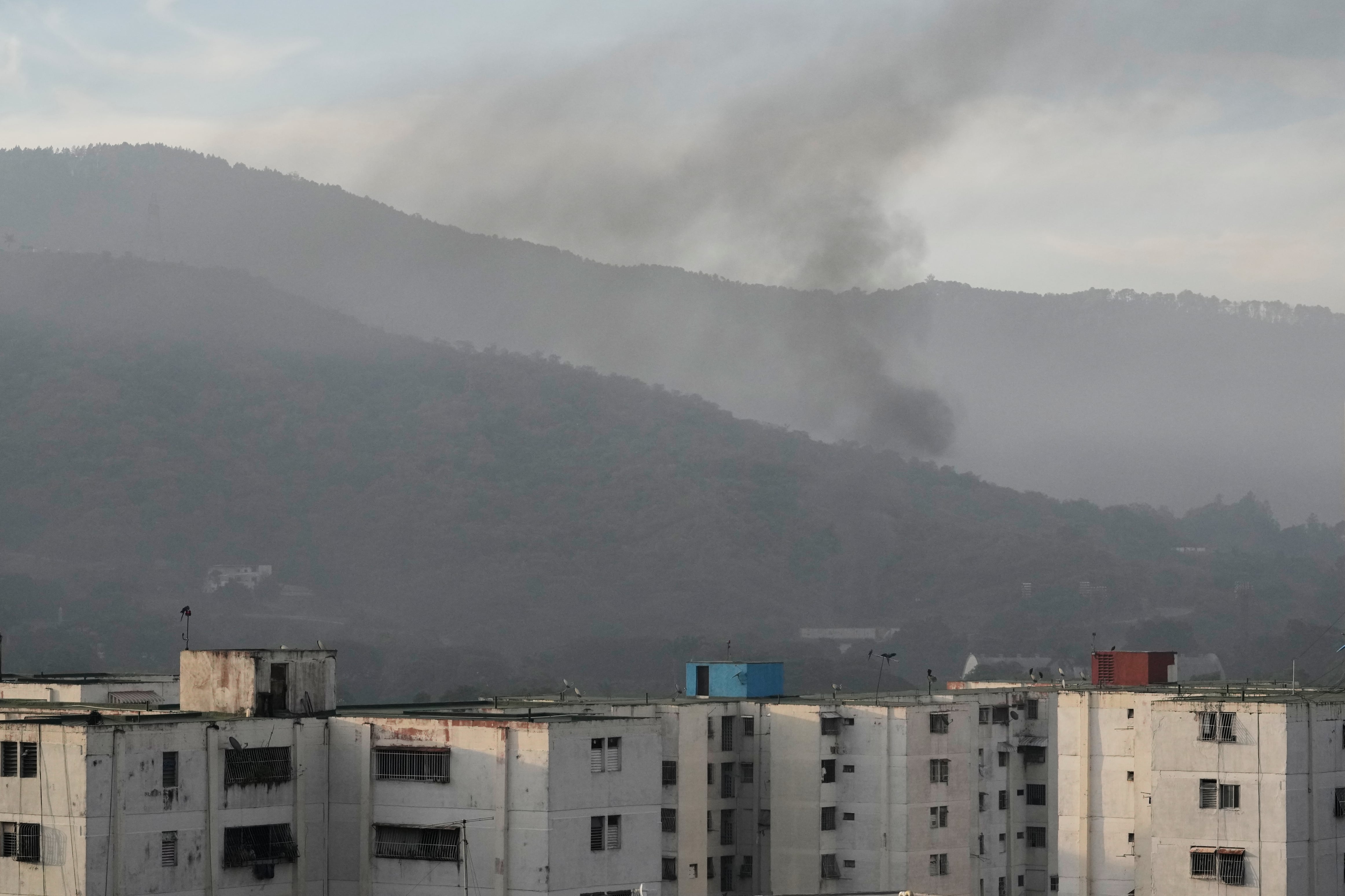 El humo se eleva desde Fuerte Tiuna, la principal guarnición militar en Caracas, Venezuela, después de que se escucharan múltiples explosiones y aeronaves sobrevolaran la zona, el sábado 3 de enero de 2026. (AP/Matias Delacroix)