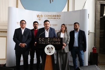 Seis personas posan frente a una mampara del Congreso de la República de Guatemala mientras un hombre sostiene un documento dentro de una carpeta