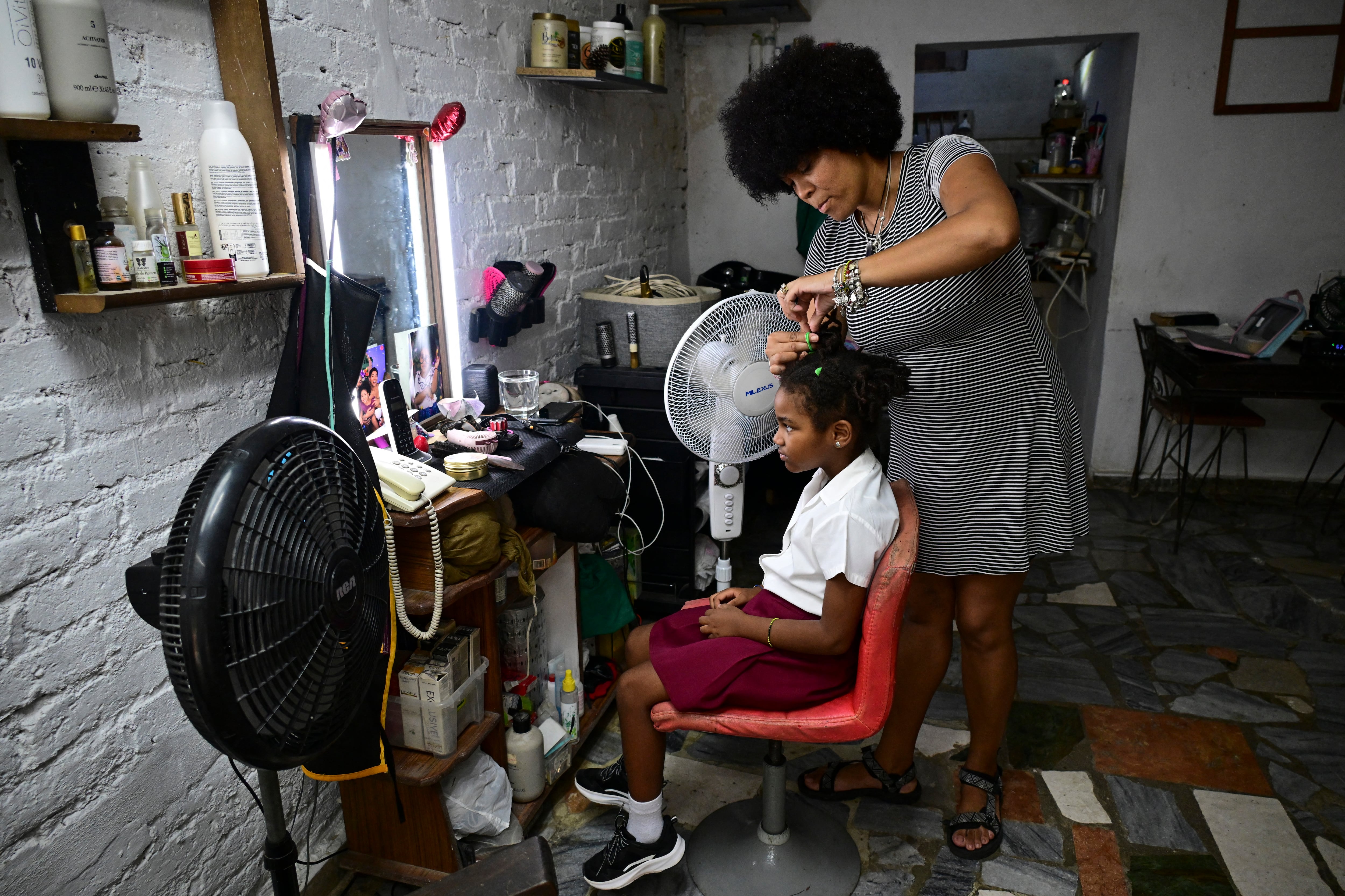 Yannay Miranda peina a su hija, Olaya Triana, mientras esta se prepara para ir a la escuela en el primer día del curso escolar 2026-2027, en La Habana, el 1 de septiembre de 2026. En medio de la escasez de uniformes y de maestros, así como de prolongados cortes de electricidad, 1,4 millones de estudiantes iniciaron un nuevo año escolar el 1 de septiembre en Cuba, donde la crisis económica obliga a las familias a asumir los crecientes costos de la educación de sus hijos. (Foto de YAMIL LAGE / AFP)