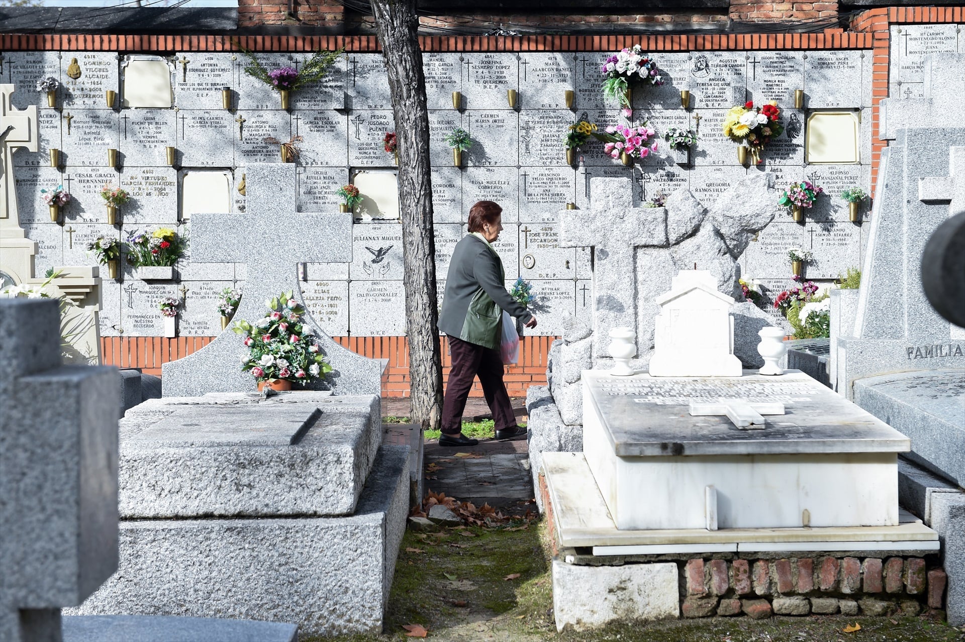 Una mujer con un ramo de flores en el Cementerio de la Almudena de Madrid. (Gustavo Valiente / Europa Press)