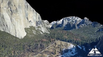 Modelo digital en tres dimensiones de una pared rocosa vertical, un valle arbolado y montañas nevadas sobre un fondo negro
