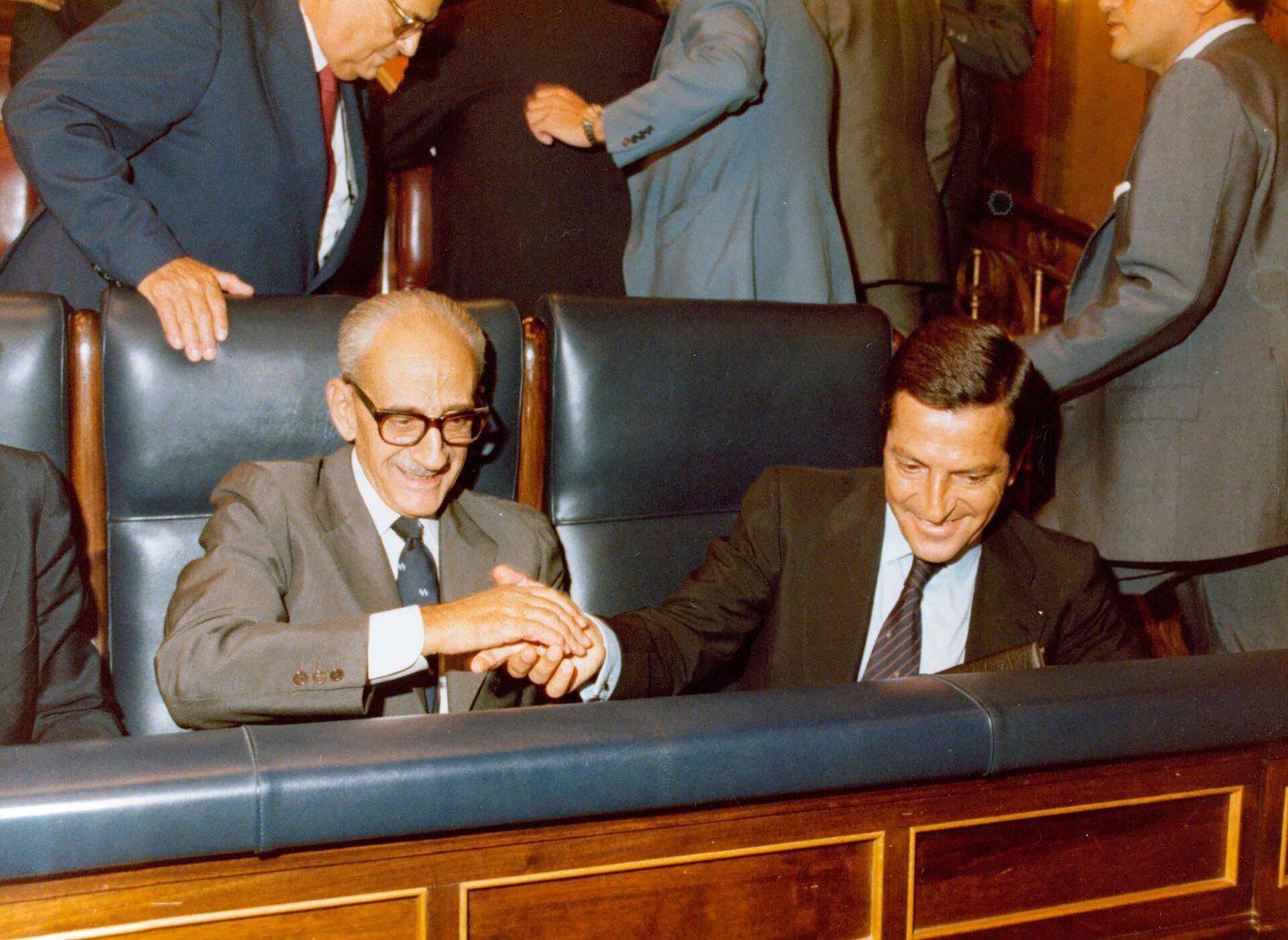Adolfo Suárez y Manuel Gutiérrez Mellado (de lentes) sentados en el Congreso de los Diputados. Suárez y Gutiérrez Mellado, junto con el comunista Santiago Carrillo, fueron las tres únicas personas que no se tiraron al suelo cuando los guardias civiles dispararon al aire con sus subfusiles (Ministerio de la Presidencia. Gobierno de España)