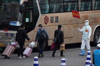 Travelers arriving from Hubei province are led to buses taking them to their individual districts, at Beijing West Railway Station on April 10, 2020. - All travelers from Hubei and its capital Wuhan, the epicenter of the COVID-19 coronavirus outbreak, must go through 14-day quarantines on arrival in Beijing. Thousands have left Wuhan since April 8, when a 76-day travel ban was lifted on the Chinese city where the coronavirus first emerged. (Photo by GREG BAKER / AFP)