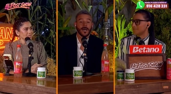 Adolfo Aguilar, un hombre con barba grisácea y traje oscuro, habla en un micrófono mientras está sentado entre dos mujeres en un estudio de televisión