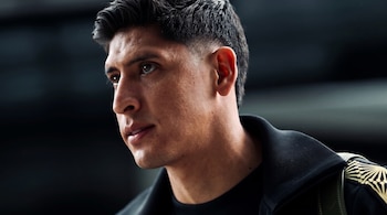Primer plano de tres cuartos del rostro de Edson Álvarez con el cabello corto y una chaqueta negra sobre un fondo neutro.