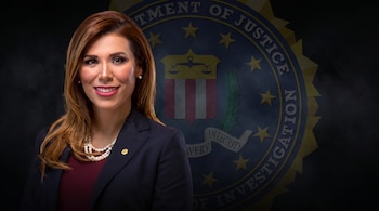 Una mujer con cabello castaño, saco oscuro, blusa vino y collar de perlas sonríe ante una cámara; el escudo del FBI se desvanece en el fondo oscuro.