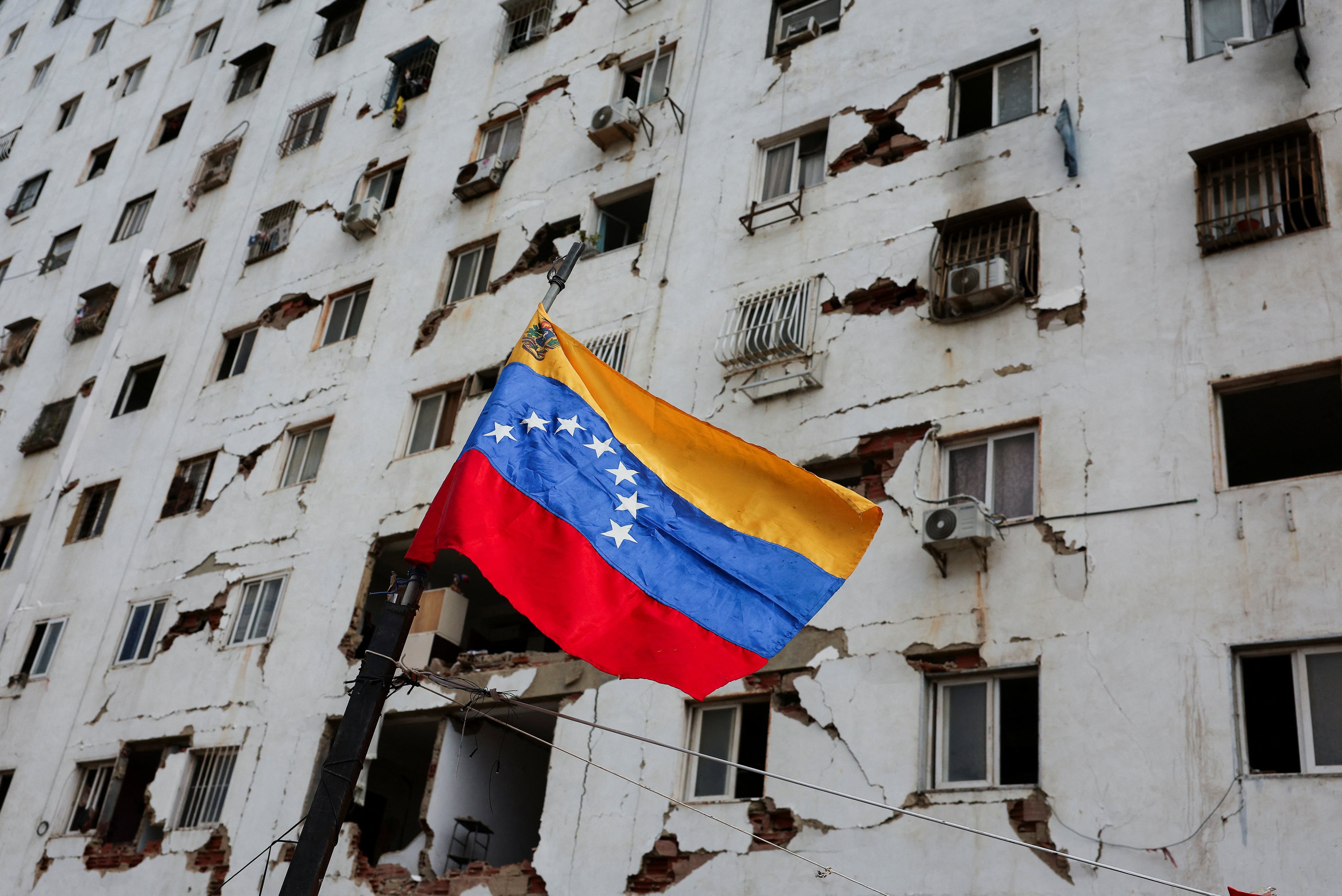 Una bandera venezolana ondea junto a un edificio dañado, tras los mortíferos terremotos del 24 de junio, en La Guaira (Venezuela), el 6 de julio de 2026. REUTERS/Gaby Oraa