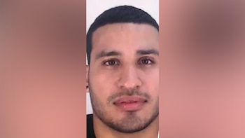 Primer plano del rostro de un hombre con pelo corto oscuro, barba incipiente y ojos marrones claros, mirando directamente a la cámara